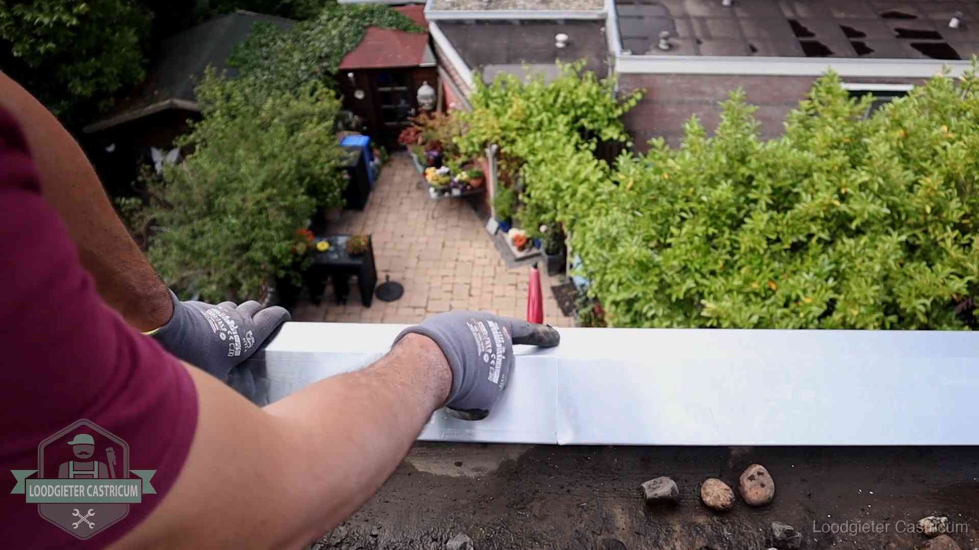 Vakman plaatst een daktrim op de dakrand van een woning in Castricum