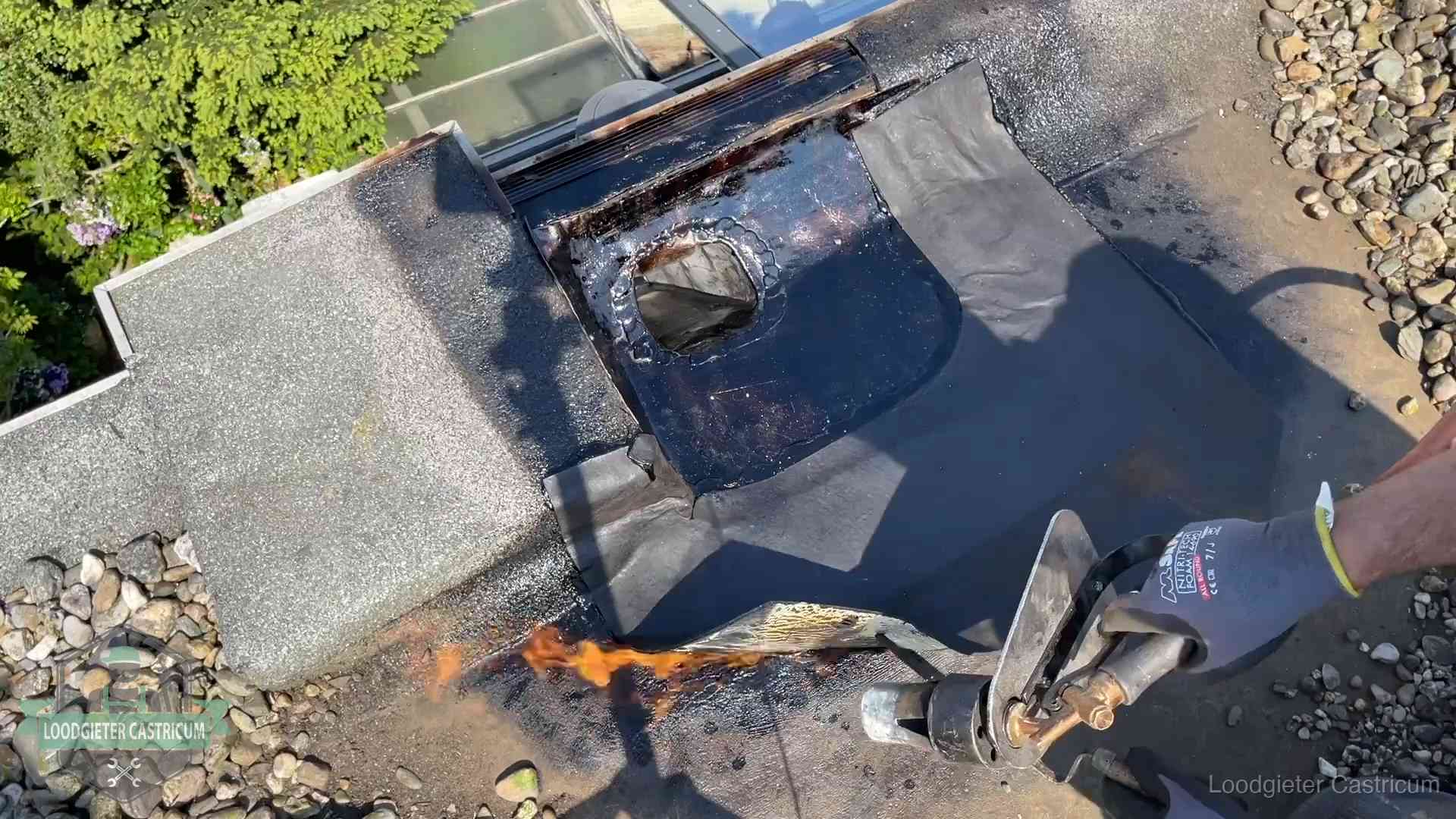 Dakdekker brandt bitumen rond een doorvoer tijdens een daklekkage-reparatie in Castricum