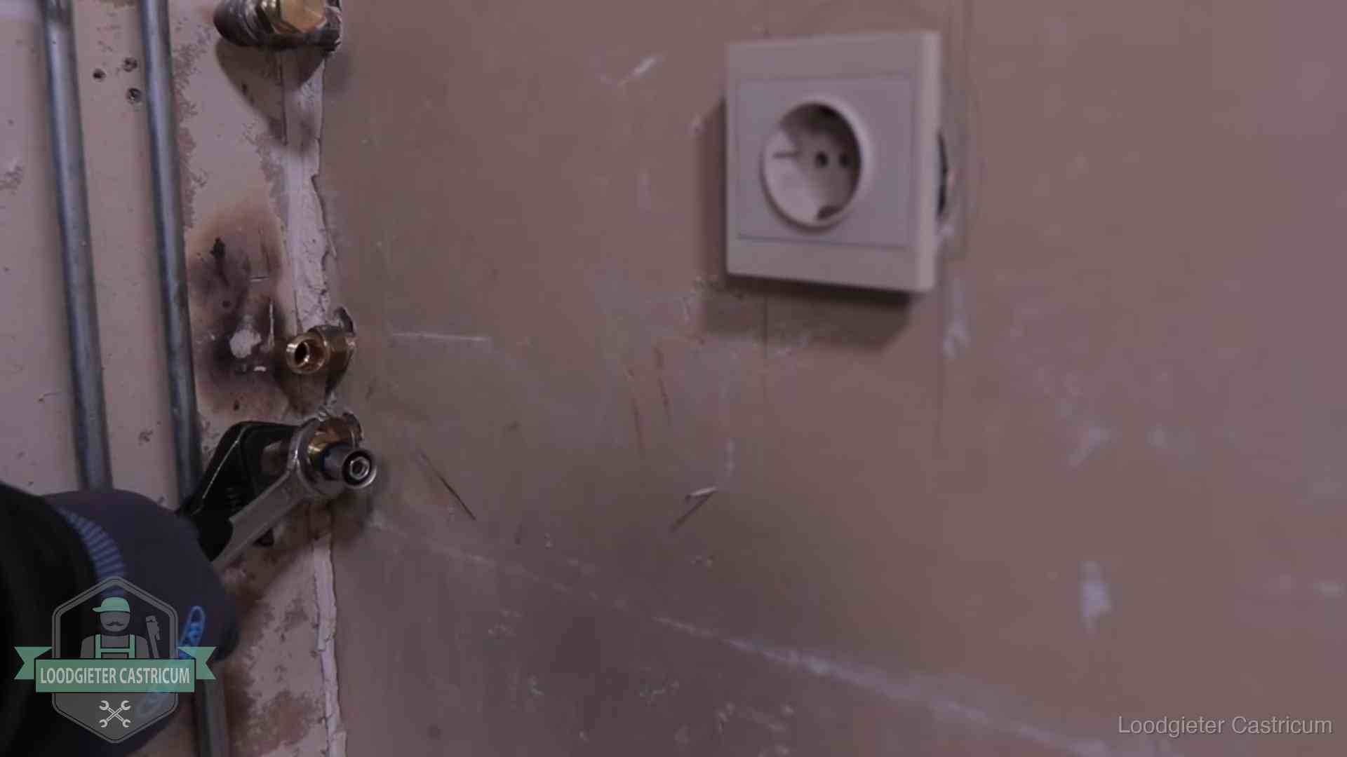 Monteur draait een perskoppeling vast op een leidingaansluiting in Castricum