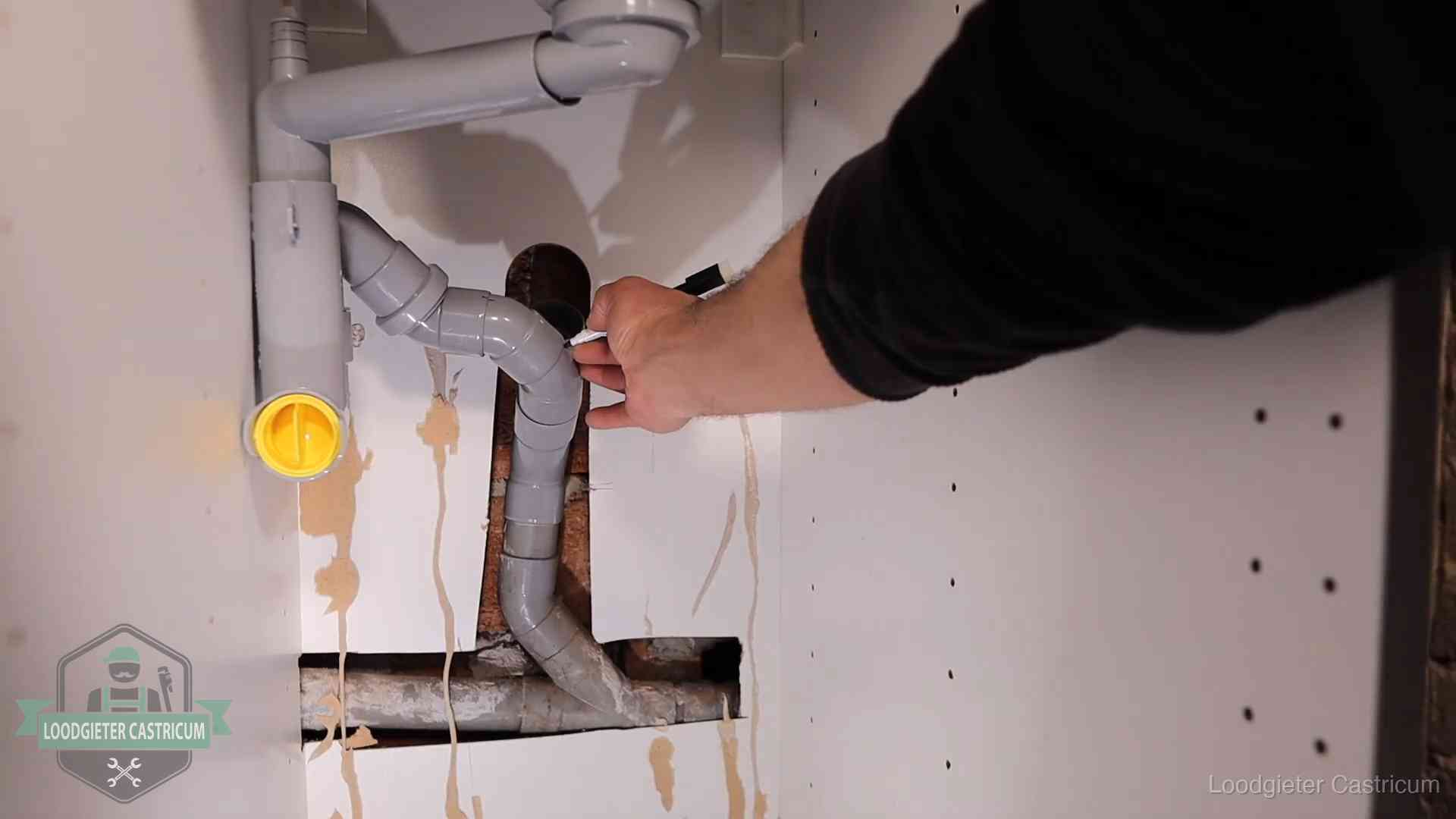 Loodgieter markeert een pvc-afvoerbuis onder een gootsteen in Castricum