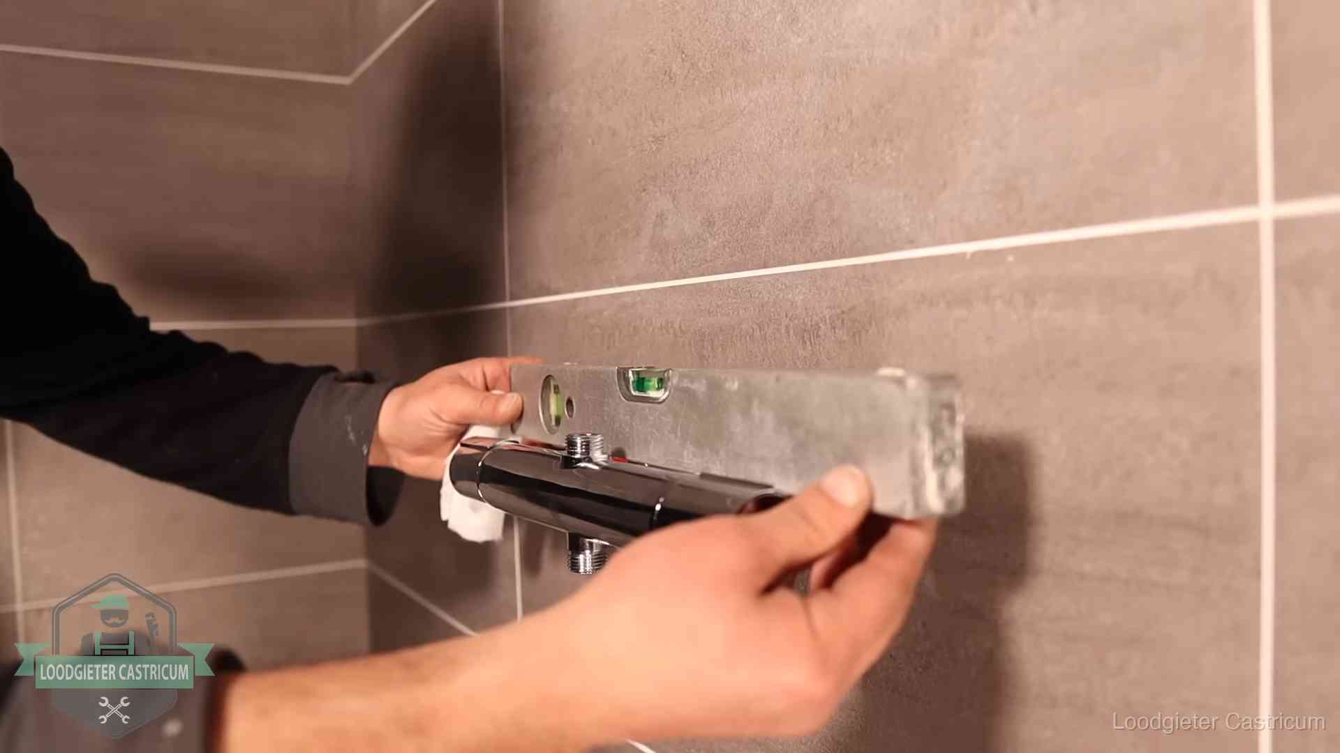 Loodgieter lijnt een douchekraan uit met een waterpas in een woning in Castricum