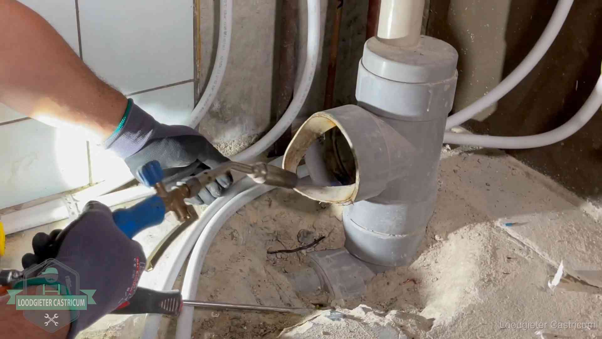 Loodgieter werkt met brander en messing kraanwerk aan leidingen in Castricum