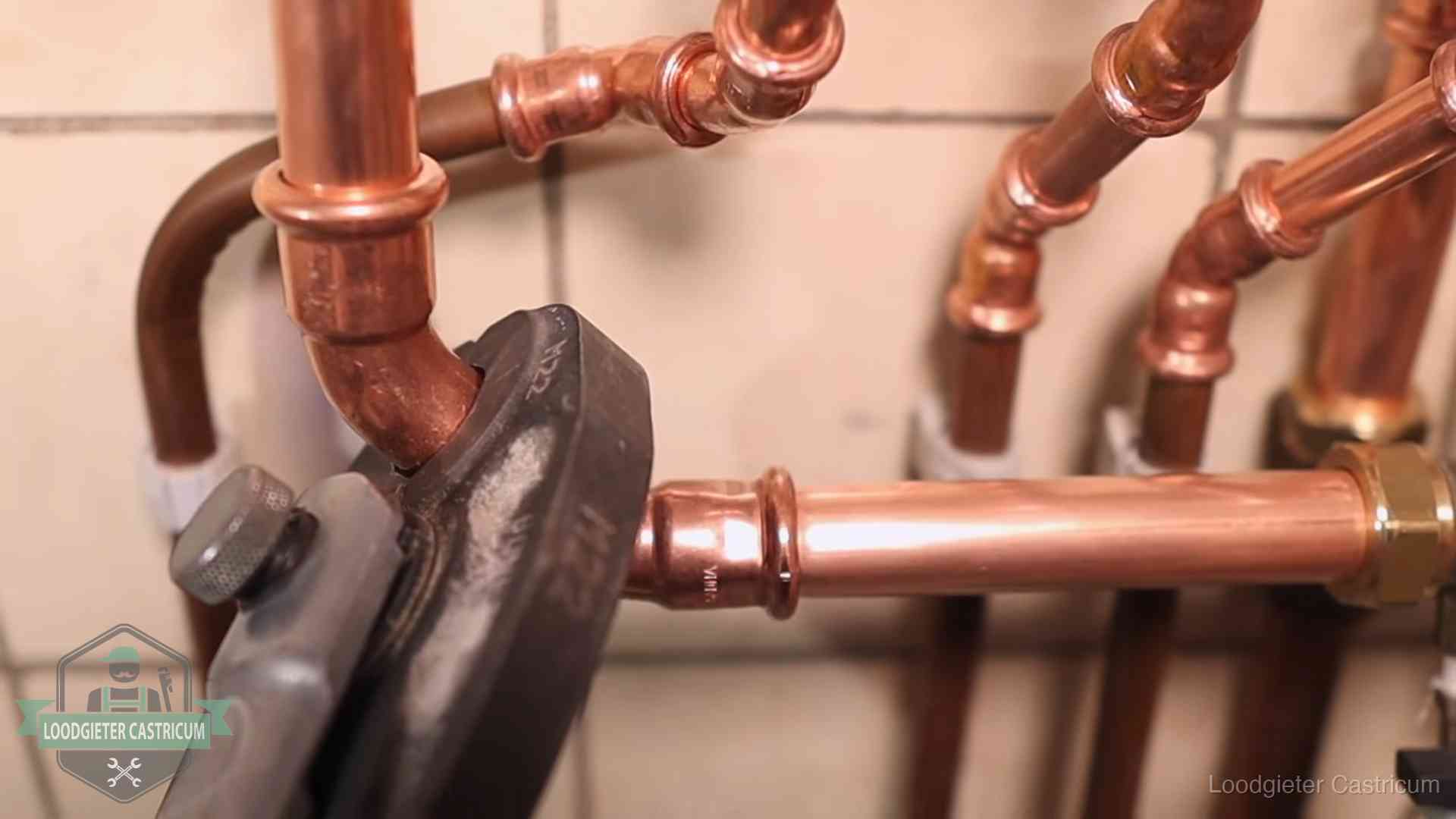 Persmachine perst een koperen fitting op nieuw leidingwerk in Castricum